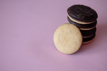 A pile of Jaffa cakes. Cookies covered with dark chocolate and filled with purple strawberry or cherry marmalade. Delicious biscuits isolated on pink background with copyspace