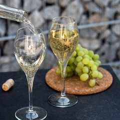 Waiter pouring white wine on outdoor cafe terrace in sunny summer day