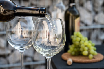 Waiter pouring white wine on outdoor cafe terrace in sunny summer day
