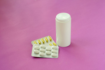 pharmaceutical medicine pills, tablets and capsules and bottle on pink background. Copy space