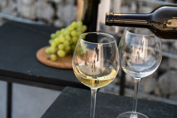 Waiter pouring white wine on outdoor cafe terrace in sunny summer day