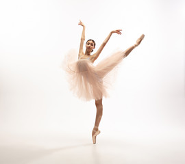 Fototapeta na wymiar Graceful classic ballerina dancing, posing isolated on white studio background. Tender peach tutu. The grace, artist, movement, action and motion concept. Looks weightless, flexible. Fashion, style.