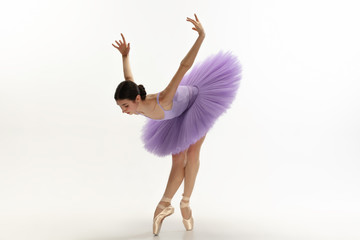 Graceful classic ballerina dancing, posing isolated on white studio background. Bright purple tutu....