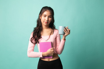 Young Asian woman with a book and cup of coffee.