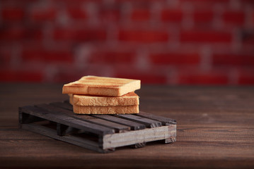 Several slices of toasted bread toasts on a wooden dark background.