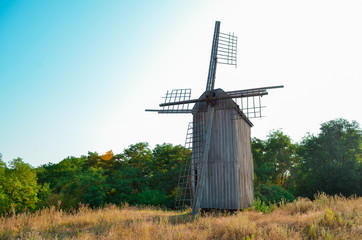 Fototapeta na wymiar Old abandoed ruined ukrainian wooden mill of nineteenth century, summer landscape with forest