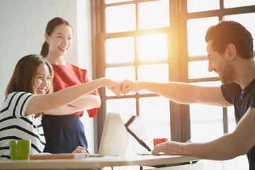 Fototapeta premium Young diverse startup team team gave a fist bump together to show greeting for project strategy has success or mission accomplished, Concept for business partnership collaboration successful, job done