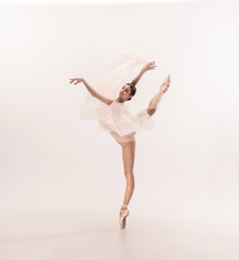 Fototapeta na wymiar Graceful classic ballerina dancing, posing isolated on white studio background. Tender peach cloth. The grace, artist, movement, action and motion concept. Looks weightless, flexible. Fashion, style.