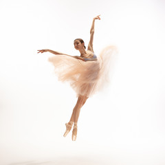 Graceful classic ballerina dancing, posing isolated on white studio background. Tender peach cloth....