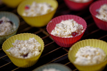 Blanks of cottage cheese cupcakes in multi-colored silicone molds. The preparation of the dessert. Top view.