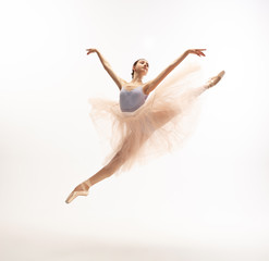 Graceful classic ballerina dancing, posing isolated on white studio background. Tender peach cloth. The grace, artist, movement, action and motion concept. Looks weightless, flexible. Fashion, style. © master1305