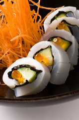 Squid rolls with salmon eggs  on a black dish