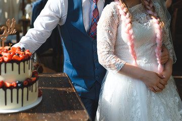 groom hugging bride at wedding cake