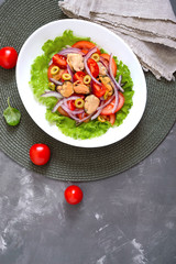 Salad of marinated mussels, fresh tomatoes, red onions, olives in a white bowl. The top view