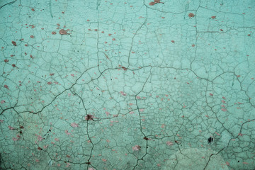 Background. Concrete wall with cracks is painted with green paint splattered with cement solution.