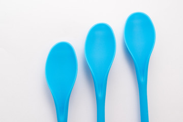 three blue kitchen plastic spoons on white background