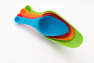 four multi-colored plastic kitchen spoons on white background