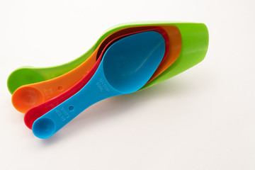 four multi-colored plastic kitchen spoons on white background