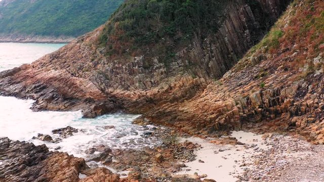 White sea waves splashing on cliffs and rocky sharp slopes of tropical island coastline in Sai Kung, Hong Kong