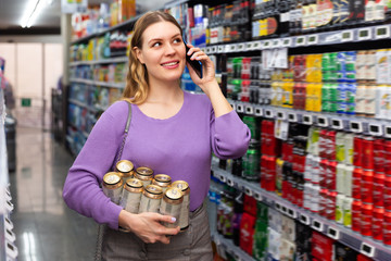 Adult woman talking by phone while choosing beer