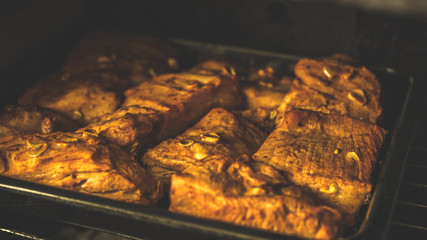 Close up of baked pork ribs on tray in oven. Seasoned meat with garlic fried in oven.