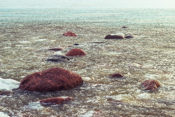 plates of melting ice cover the surface of the water near the shore
