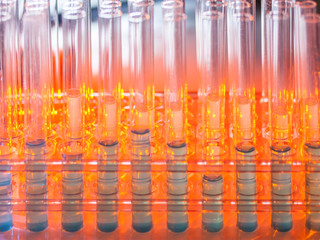 Glass test tubes containing blue liquid on warm orange background. Laboratory, science and research...
