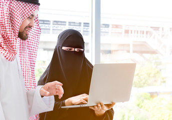 Arabian businessman & Secretary wearing hijab using laptop for analyzing data
