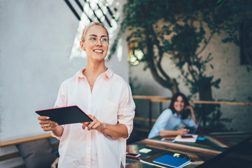 Optimistic freelancer using tablet and looking away