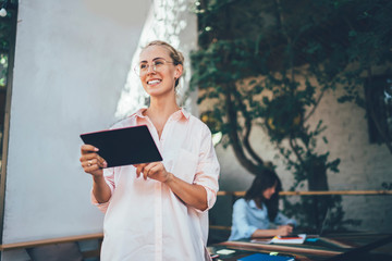 Cheerful female using tablet on restaurant terrace