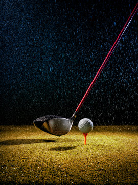 Beam Of Light In The Rain Illuminating A Golf Driver And Golf Ball On The Turf