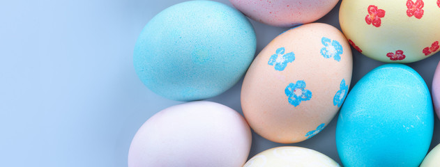 Naklejka na ściany i meble Colorful Easter hunting eggs dyed by colored water with beautiful pattern on pastel blue background, design concept of holiday, top view, copy space.
