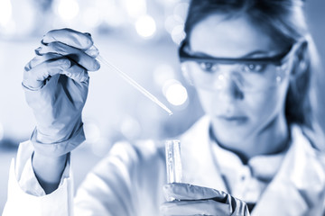 Life scientists researching in laboratory. Focused female life science professional pipetting...