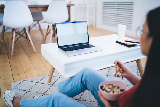 Woman looking at laptop screen and eating