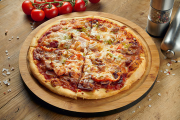 Pizza with ham, cheese, cherry tomatoes, arugula on a wooden tray. Close up. Italian cuisine