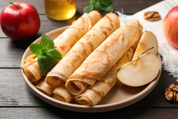 Delicious rolled thin pancakes on wooden table