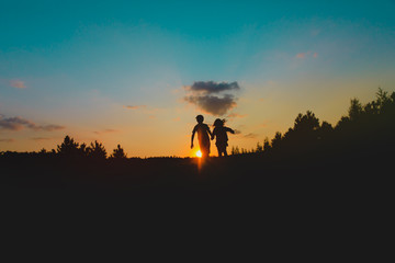 Silhouette of happy boy and girl play at sunset