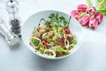 Delicious salad with seafood - salmon, shrimps, squid, lettuce and feta cheese in a ceramic plate on wooden background. CLose up