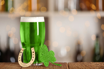 Green beer, horseshoe and clover on wooden counter, space for text. St.Patrick's Day celebration