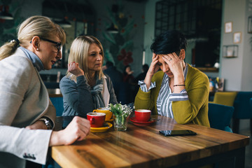 women consoling their friend at cafe
