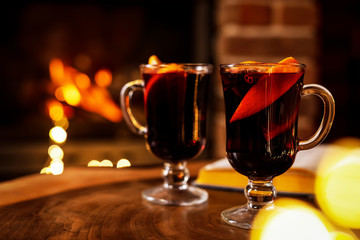 Tasty mulled wine, festive lights and blurred fireplace on background