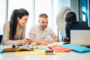 Joyful multiethnic colleagues working together at table