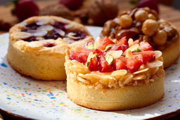Three mini tarts cupcakes with strawberries, walnuts, almond, nuts and blueberries on plate