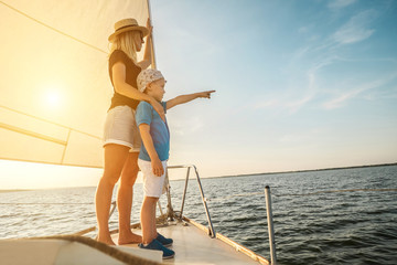 Happy traveler mother and son enjoying sunset from deck of saili