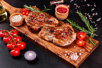 Fresh delicious juicy steak on the bones with vegetables and spices against a dark background
