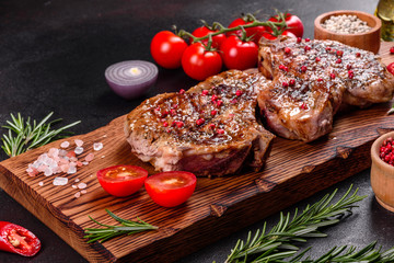 Fresh delicious juicy steak on the bones with vegetables and spices against a dark background