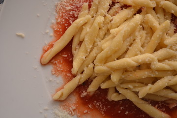 piatto di pasta trofie con burro e parmiggiano formaggio su vellutata di sugo al pomodoro