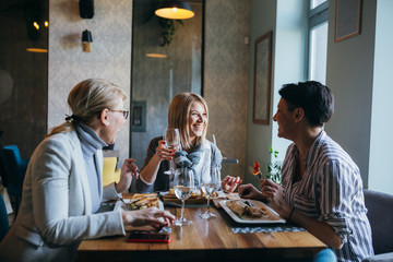 women friends making toast with wine in restaurant