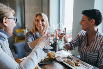 women friends making toast with wine in restaurant
