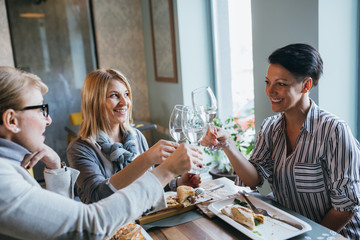 women friends making toast with wine in restaurant